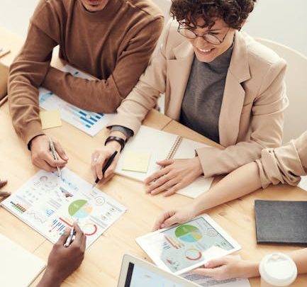 A diverse team of professionals collaborating over charts and graphs during a business meeting.