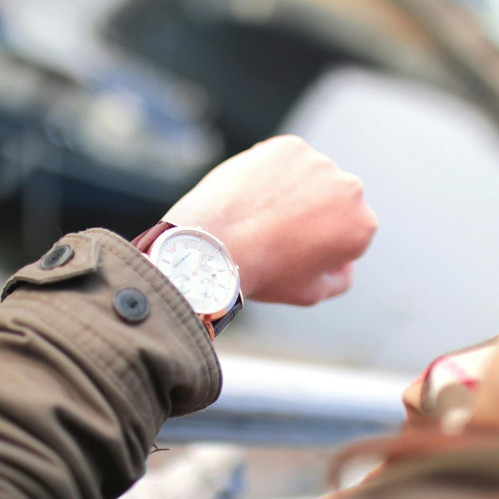 A person checks their wristwatch in a hurried outdoor setting, emphasizing time management.