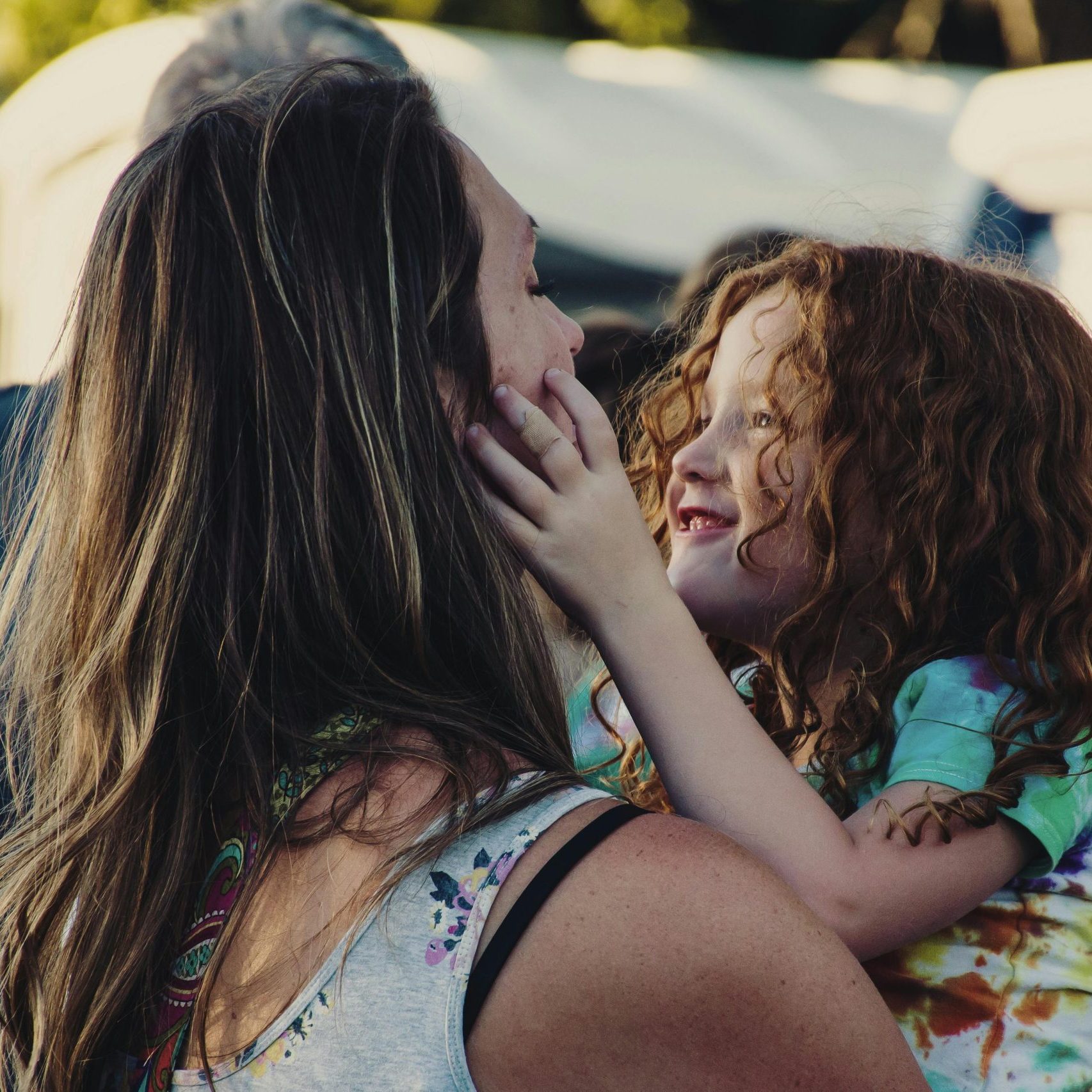 A heartwarming scene of mother and daughter embracing in a sunlit outdoor setting, symbolizing love and happiness.